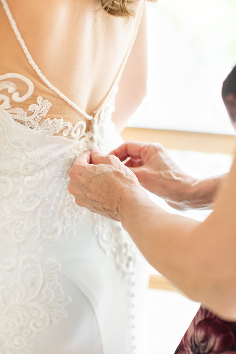 Mother of bride buttoning bride's wedding dress at Denver wedding venue.