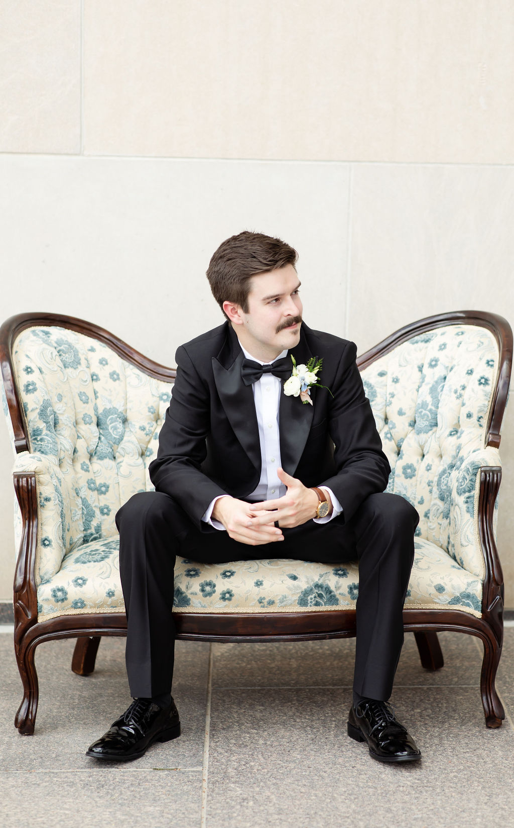 Groom sitting on vintage couch and smiling at Denver wedding venue.