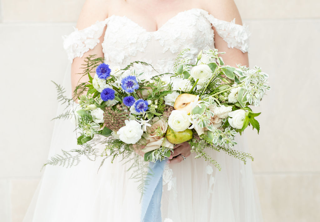 Bride holds white and blue floral bouquet at Denver wedding.