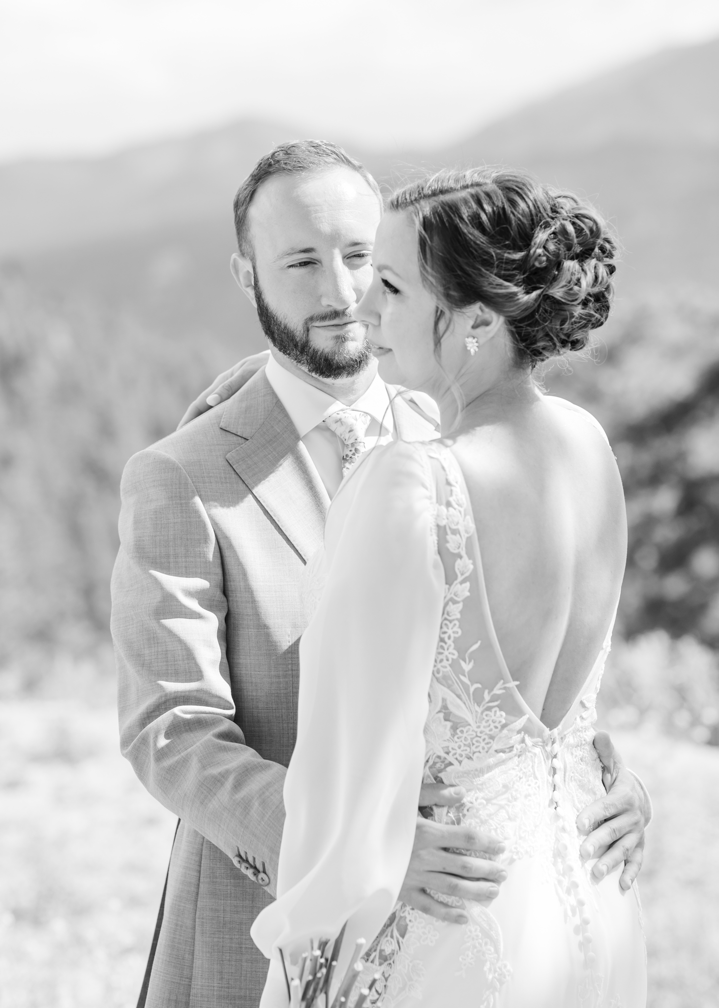 Bride looks away as groom watches her at their Denver wedding.