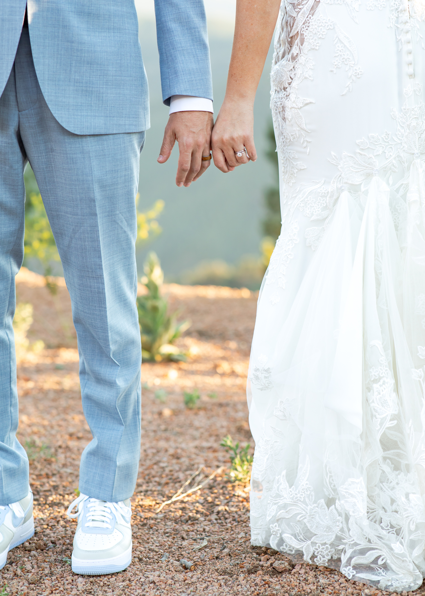 Bride and groom hold hands to show their wedding rings at their mountain wedding venue.