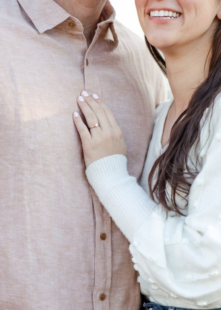 Julia rests her hand on Jonas' chest an a close view of her engagement ring.