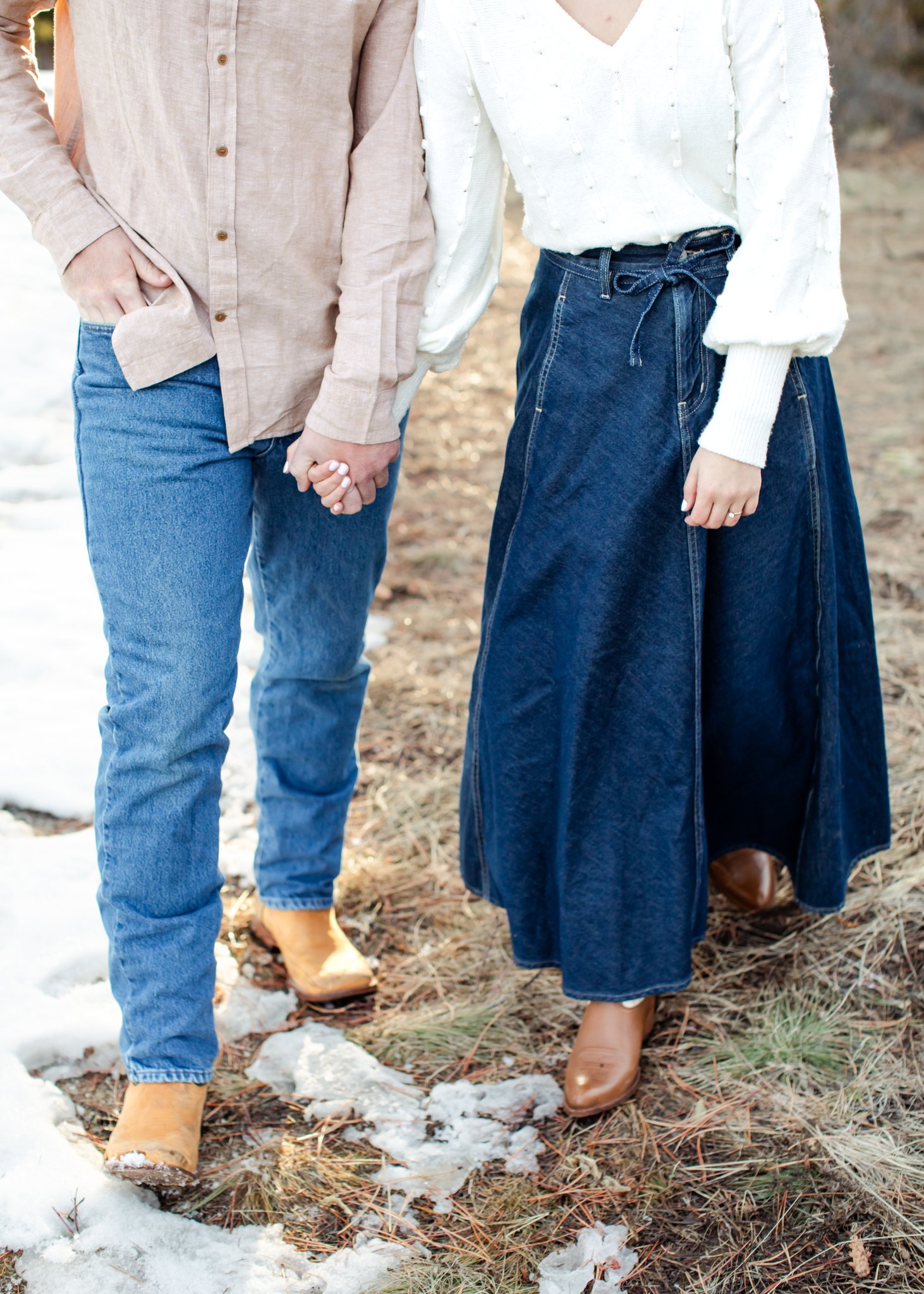 Jonas in denim jeans and boots, and Julia in a denim skirt and boots. Their legs and hands as the focal point.