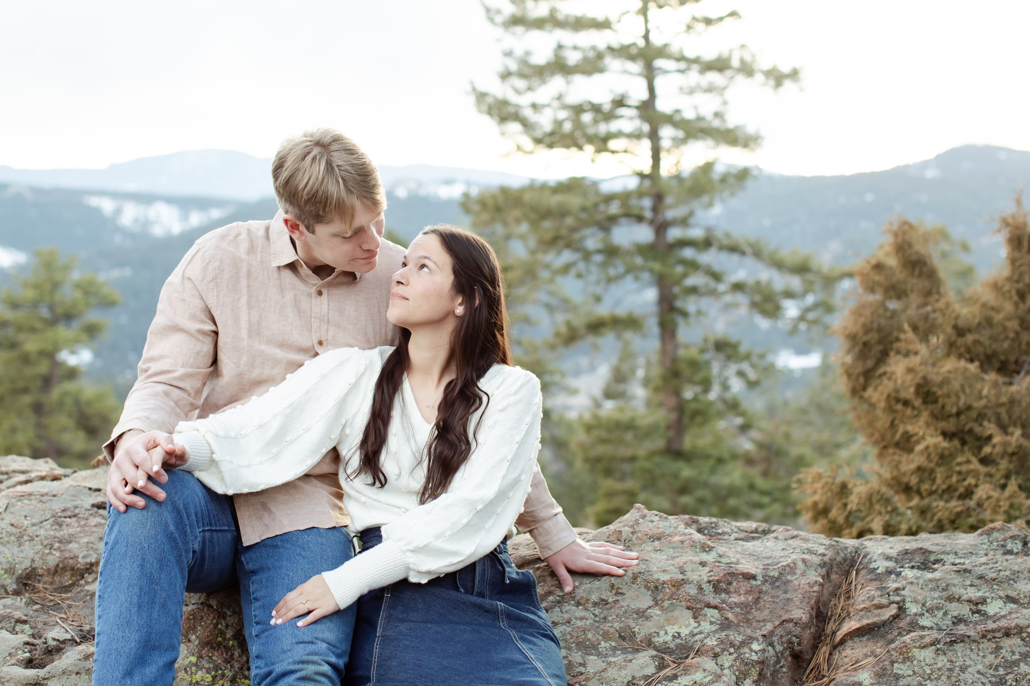 With mountains in the backdrop, Julia looks up at Jonas while they sit together.