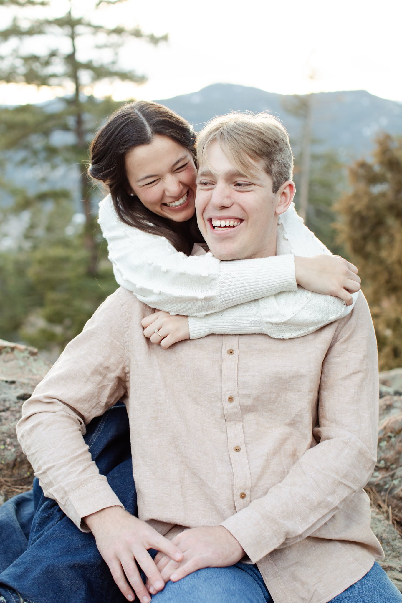 Julia laughs and scrunches her nose as she hugs Jonas from behind.