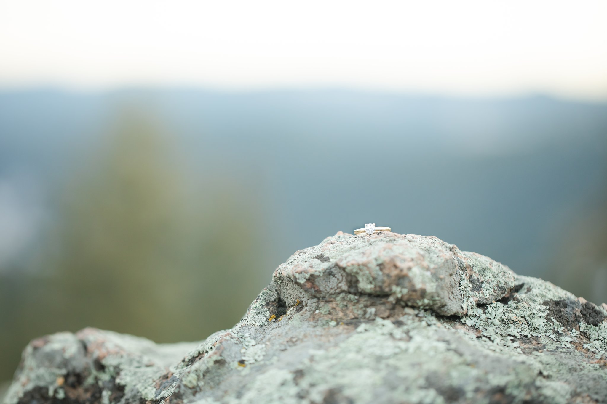 A ring sits atop a rock in focus while the mountains are blurred behind it.