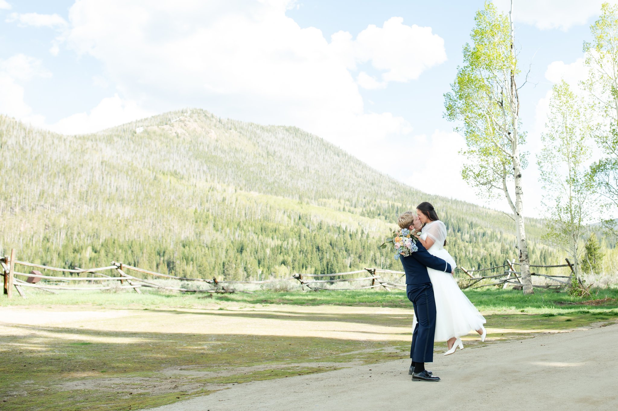 Groom picking up bride and kissing her on a mountain range in Granby Colorado.