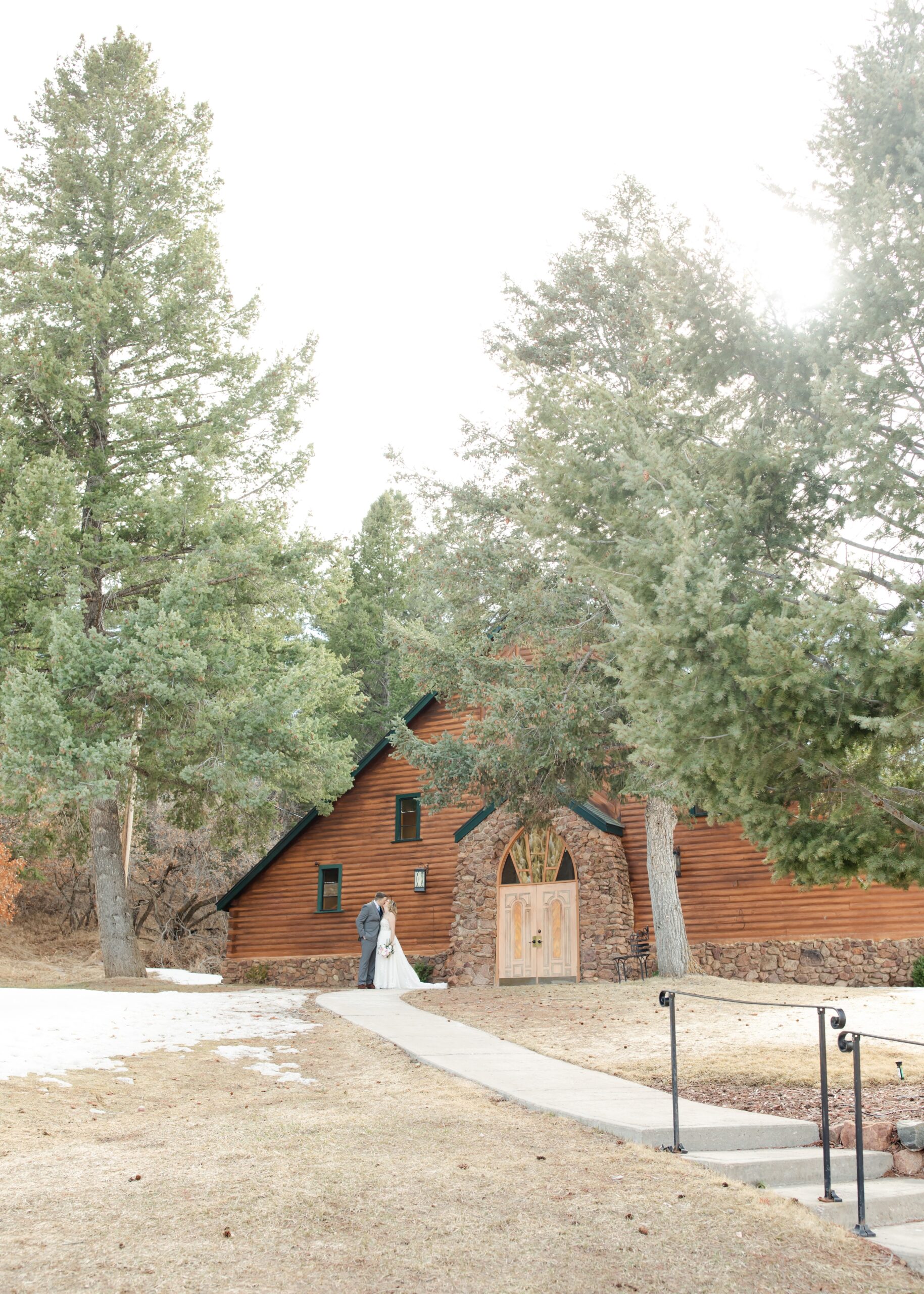Bride and groom kissing in front of Pinecrest Wedding venue as an example of what a real wedding photo looks like.