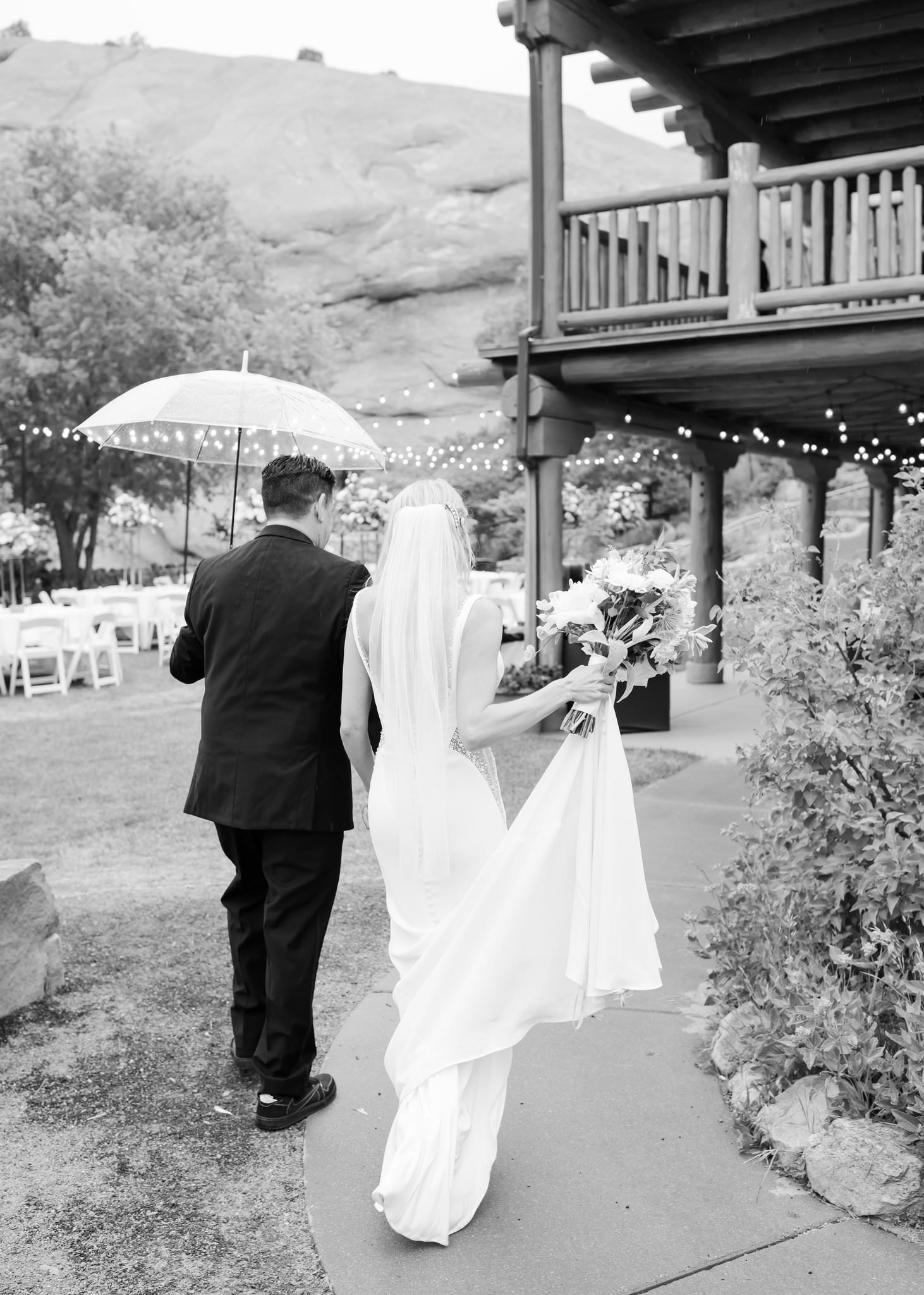 Bride and groom walking away under umbrella at Red Rocks wedding venue.