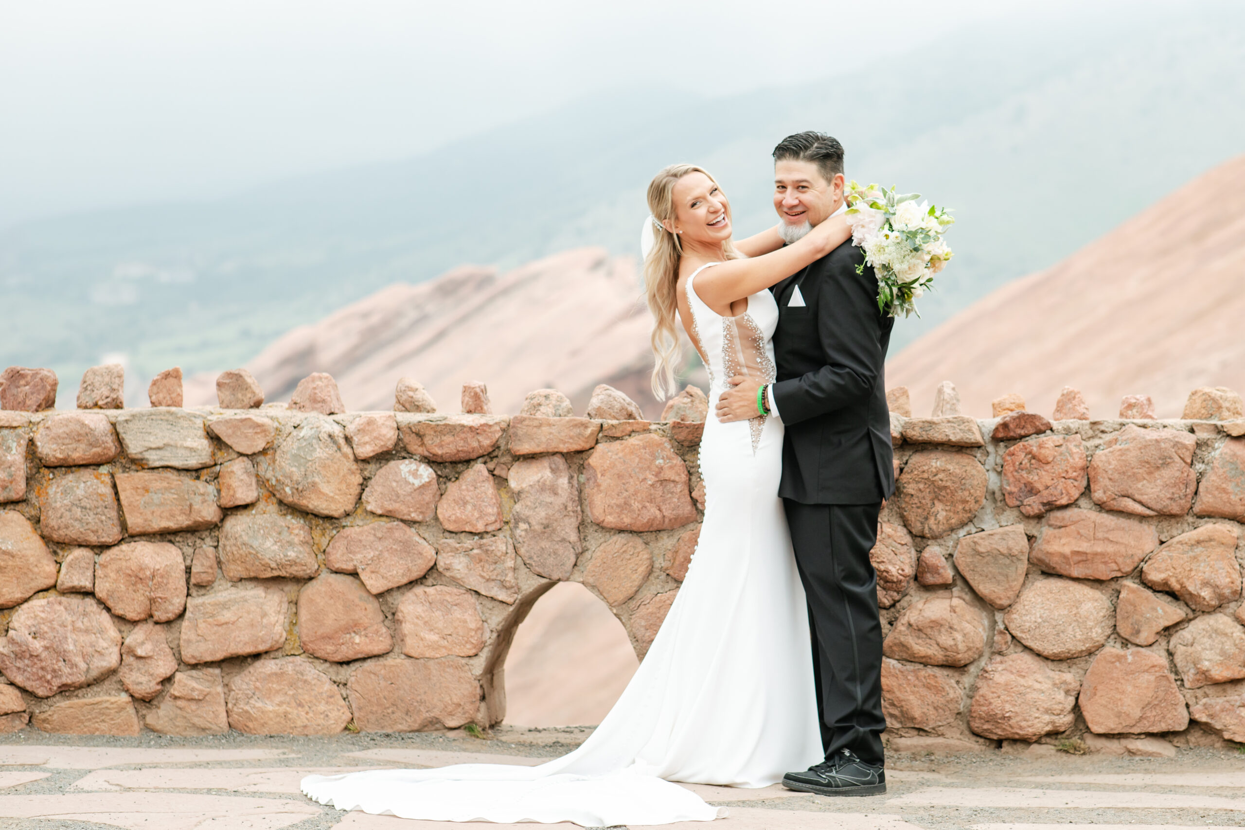 Bride and groom smile at their ceremony at Red Rocks wedding venue with mountain views.