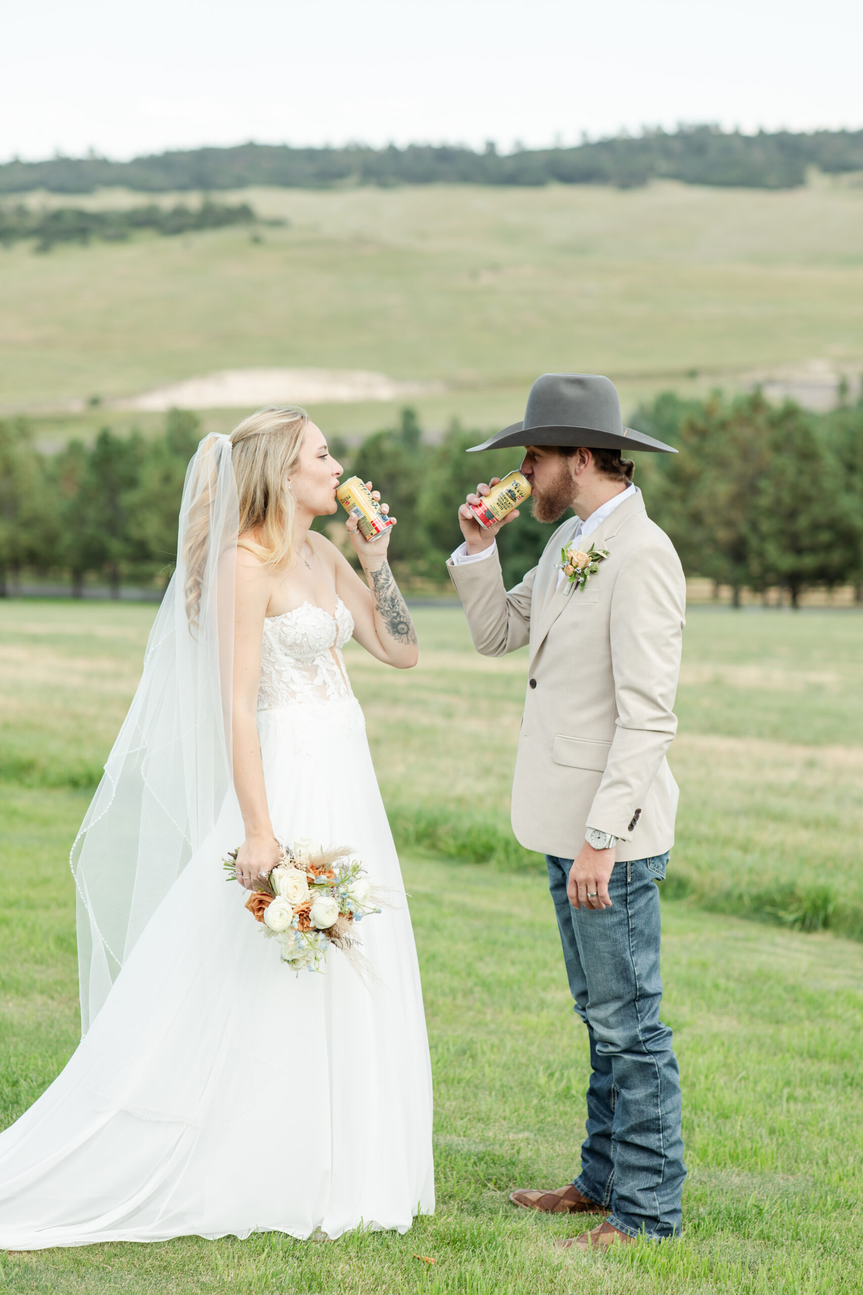 Bride and groom drink a Coors together after their wedding at Spruce Mountain Ranch wedding venue in Colorado.