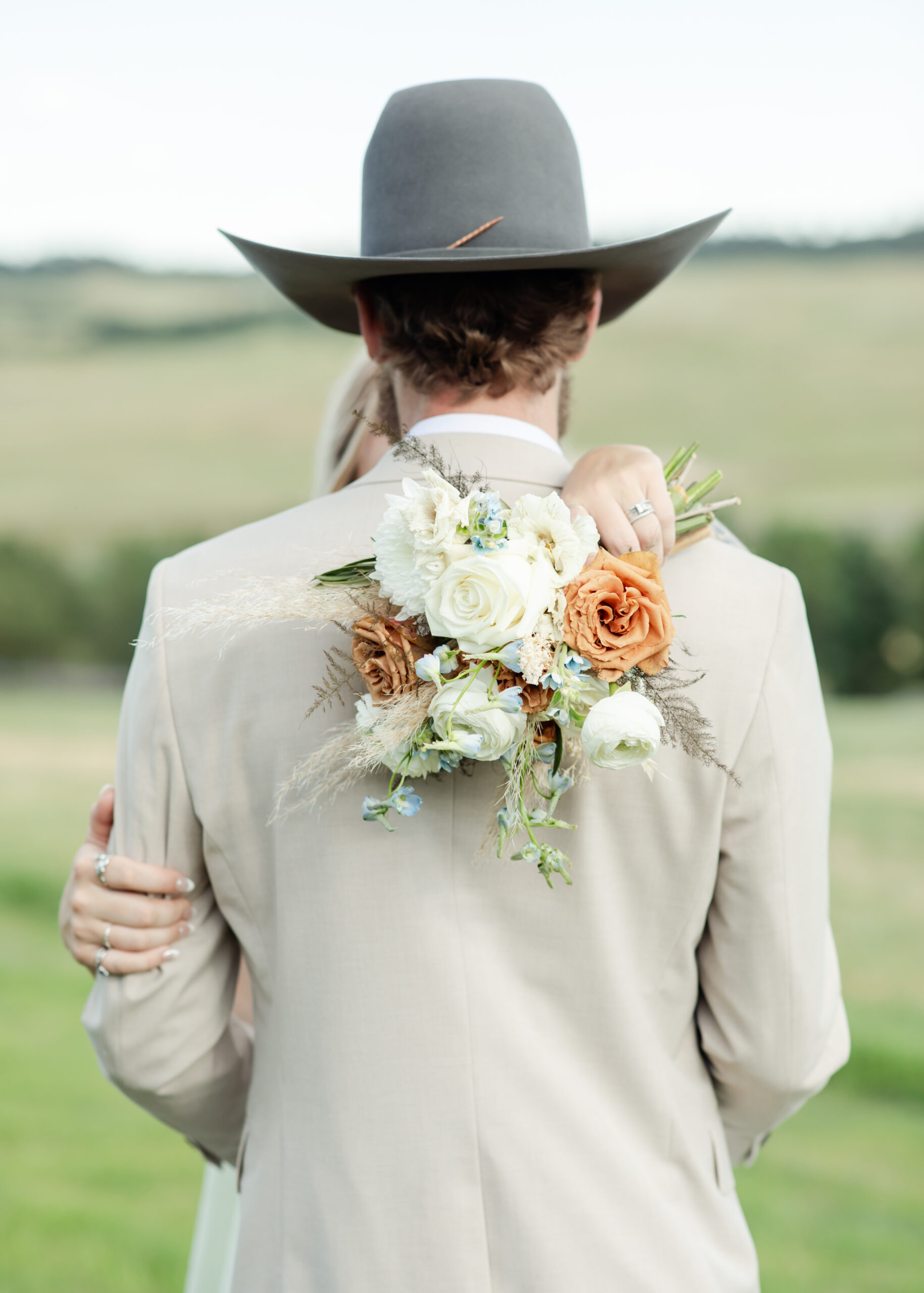Bride holds bouquet in over shoulder of groom near Colorado Springs wedding venue.