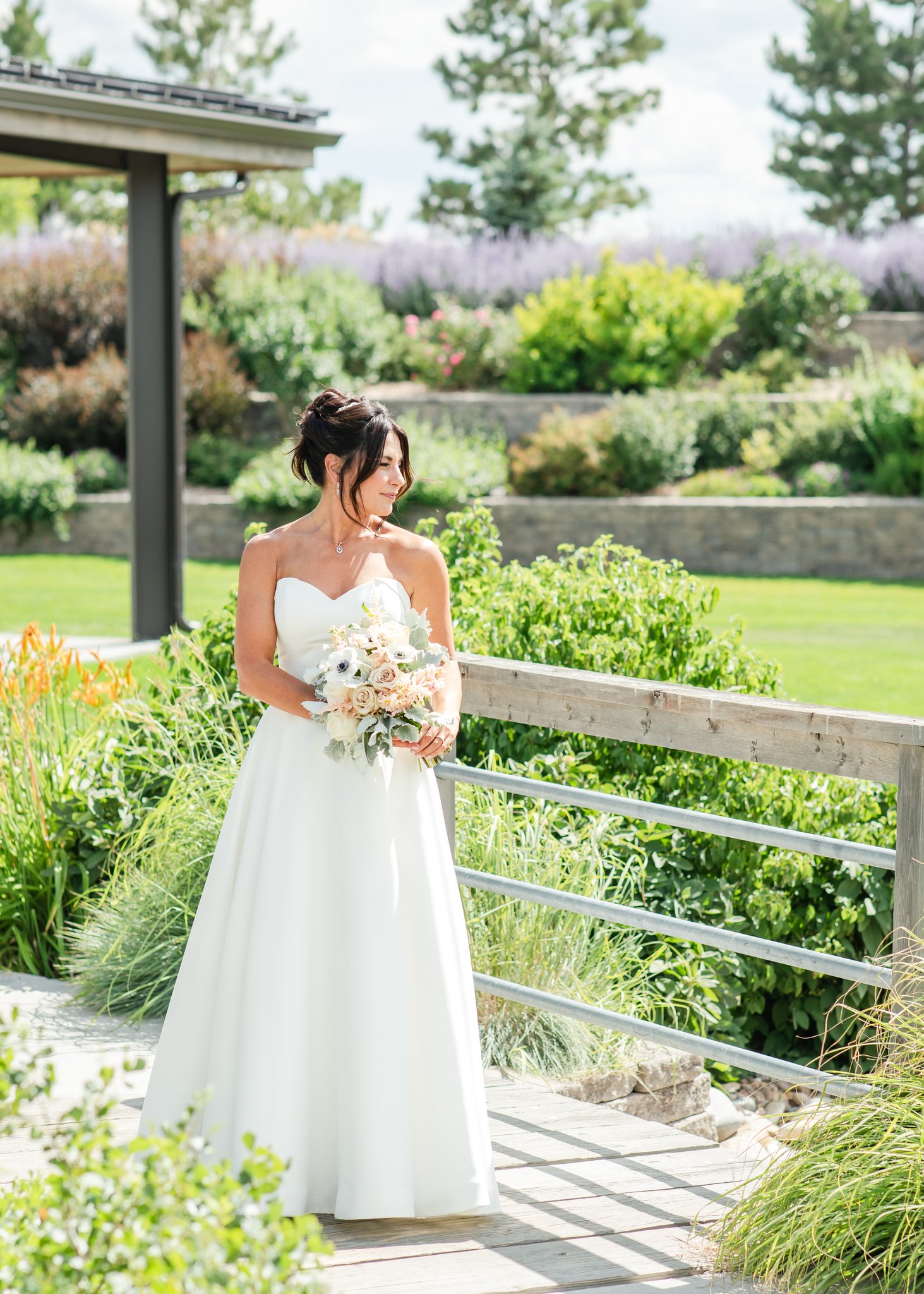 Bride stands in lush garden as an example of a wedding venue in a Colorado winery.