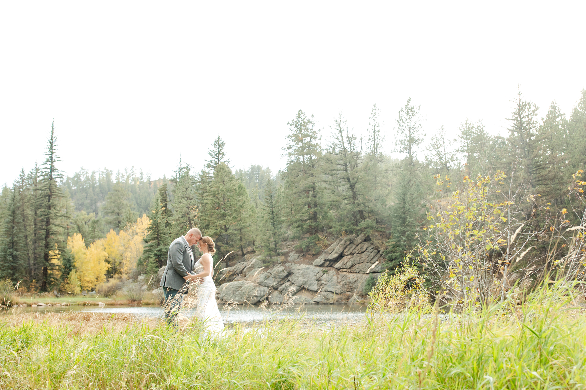 Bride and groom leaning foreheads together during their fall wedding in Colorado mountains.