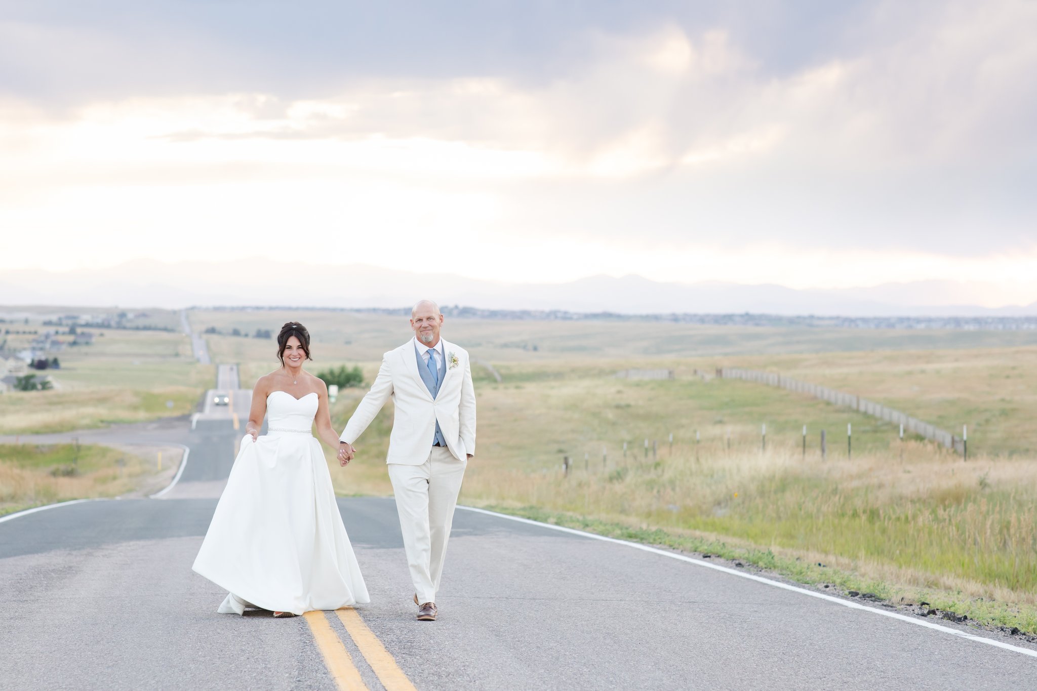 Bride and groom walking a blacktop road near all-inclusive wedding venue in Denver.