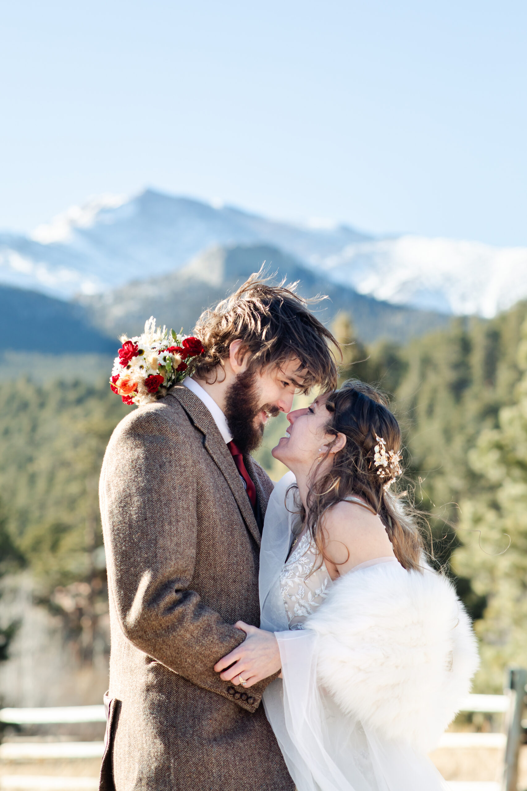 Bride and groom leaning their noses together in front of mountains at Wild Basin Lodge wedding venue near Estes Park.