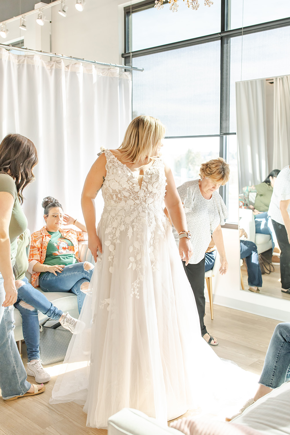 Bride looking over he shoulder at her mother while trying on a wedding dress at a Denver bridal shop.