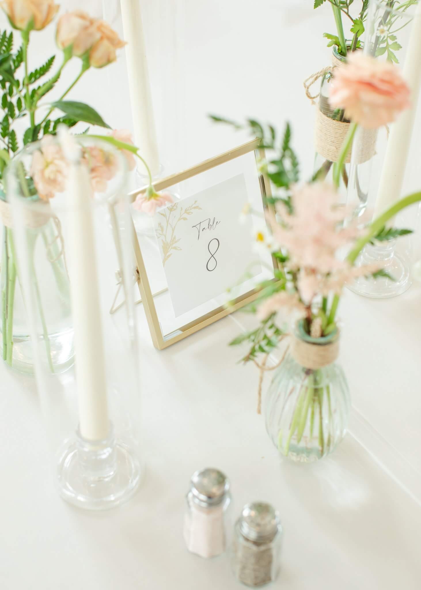 Details of a wedding reception table setting with pink roses and candles from Banks and Leaf