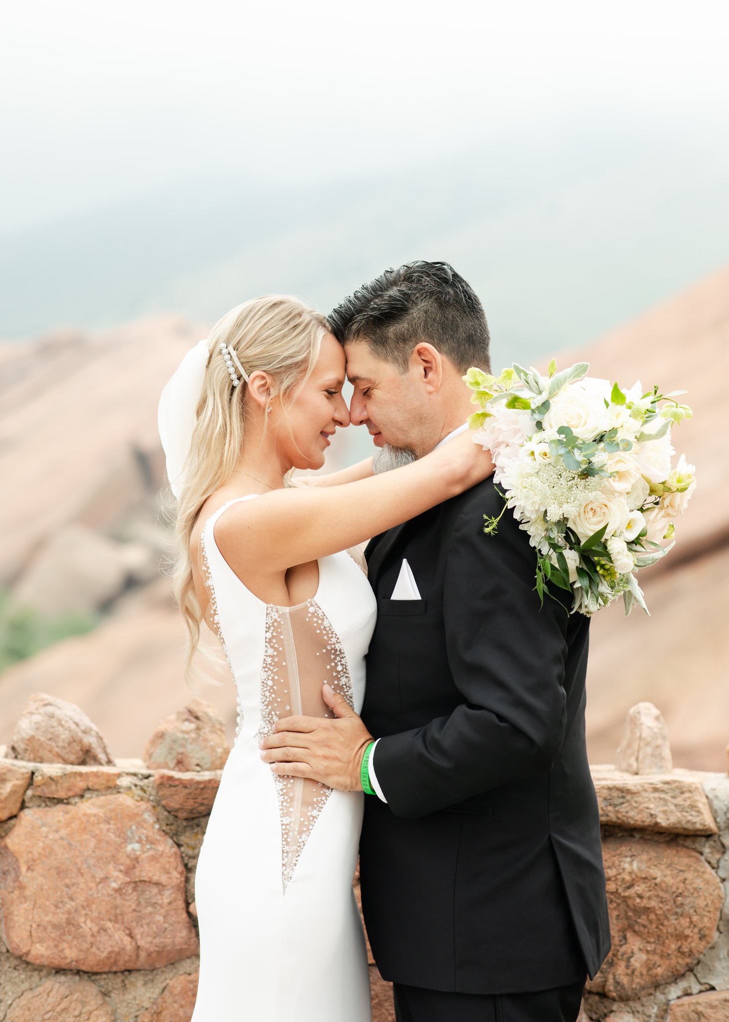 Newlyweds snuggle touching foreheads on a mountain overlook with support from Calluna Events