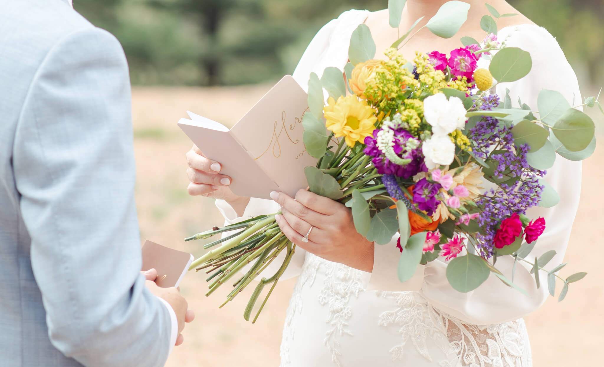 Details of a bride's colorful bouquet in her hand while reading her vows during her day supported by Table 6 Productions