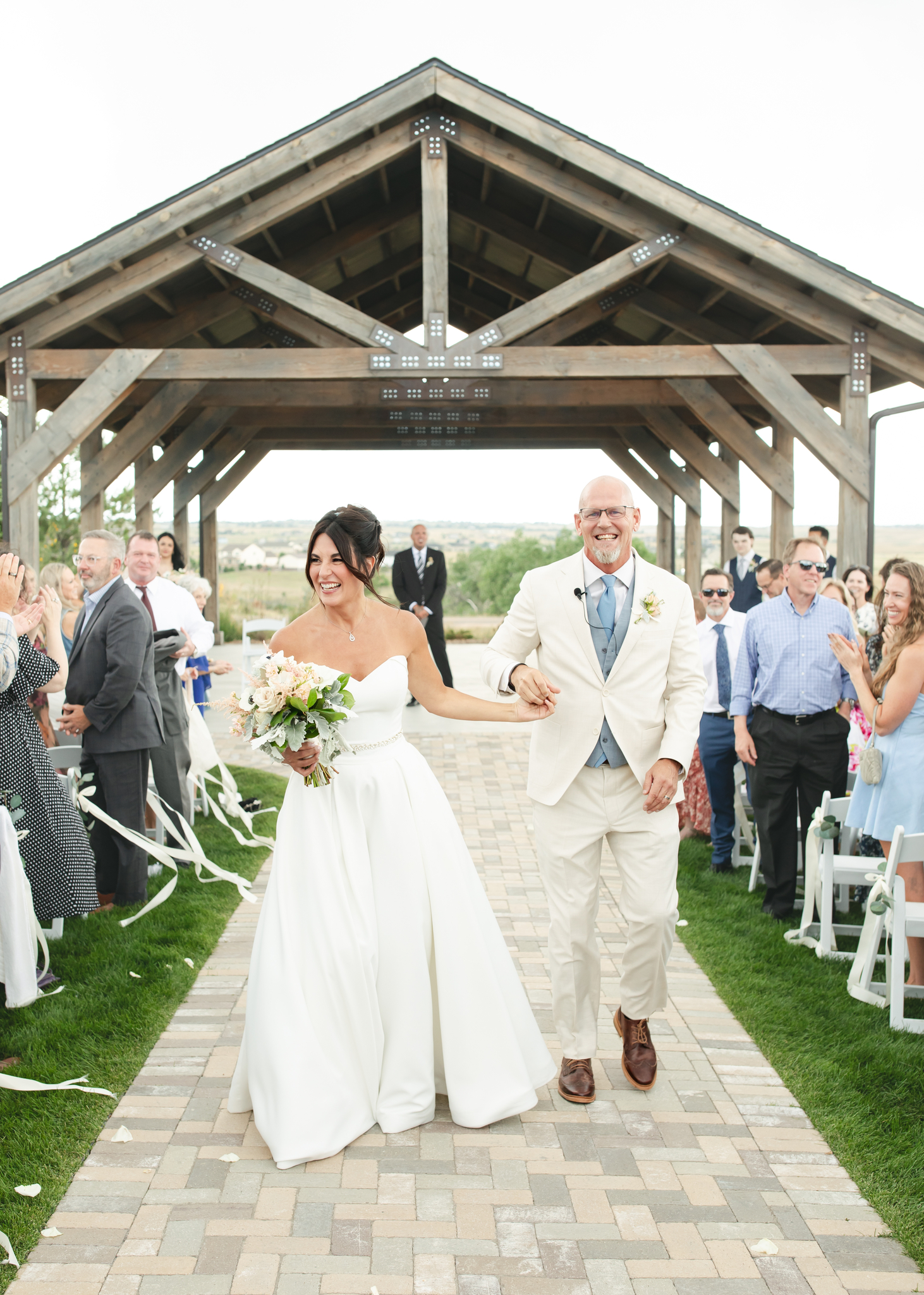 Newlyweds smile big while walking up the aisle to guests clapping